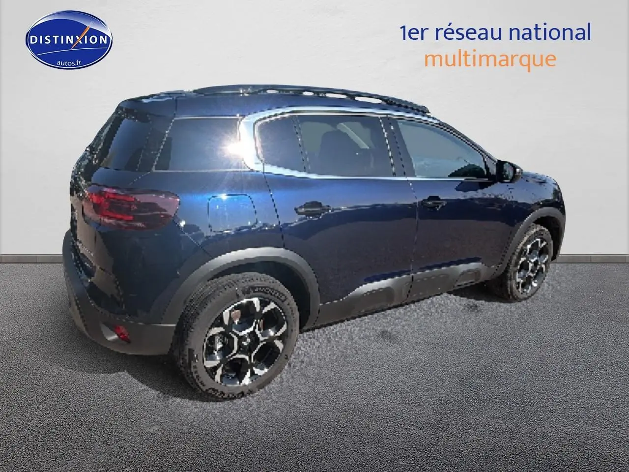 Vue 3/4 arrière droite du Citroën C5 Aircross bleu eclipse avec jantes alu et barres de toit noires.
