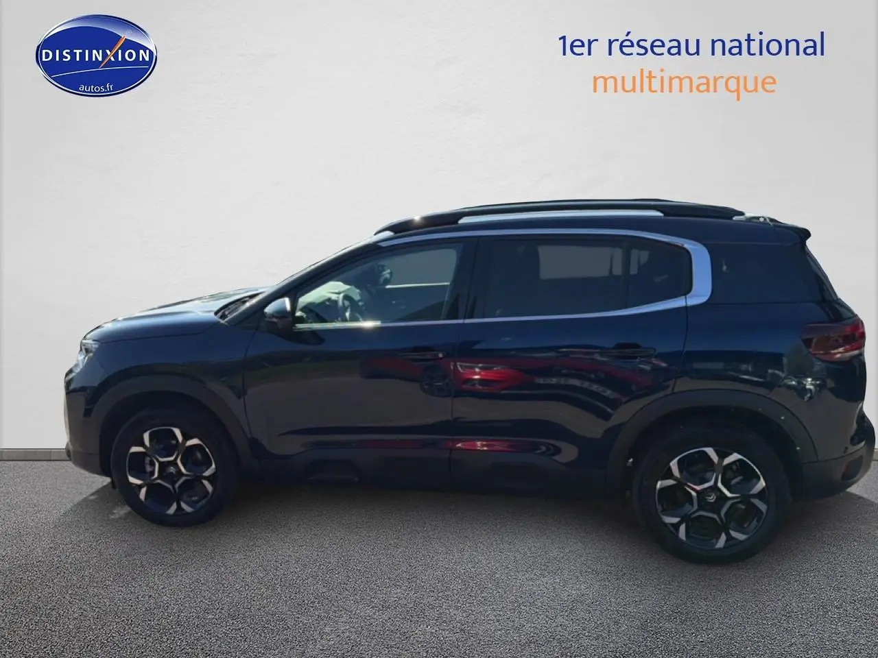 Vue de profil côté gauche d'un Citroën C5 Aircross bleu eclipse avec jantes alliage et barres de toit noires.