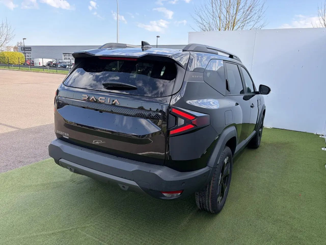 Vue 3/4 arrière droite du Dacia Bigster noir nacré avec feux arrière LED en forme de flèche et toit ouvrant panoramique.