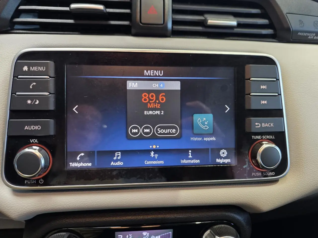 Écran tactile central de la Nissan Micra 2022, vue frontale, tableau de bord beige avec commandes audio et téléphone.