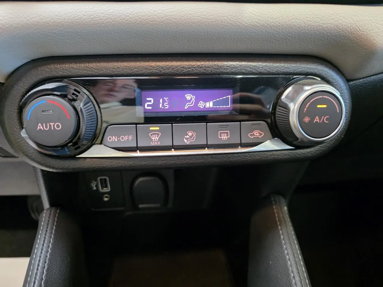 Gros plan sur la commande de climatisation automatique de la Nissan Micra gris clair, avec affichage digital à 21,5°C.