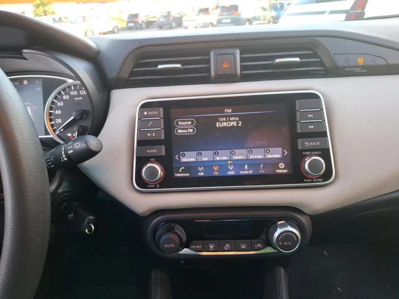 Vue intérieure du tableau de bord beige et noir de la Nissan Micra 2022 avec écran tactile radio et commandes climatisation.