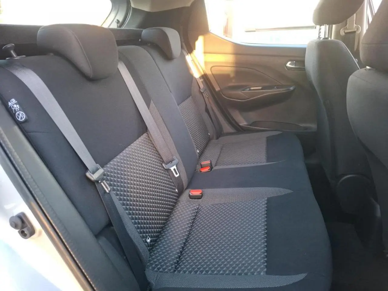 Vue intérieure côté gauche de la banquette arrière tissu noir de la Nissan Micra gris clair avec ceintures de sécurité visibles.