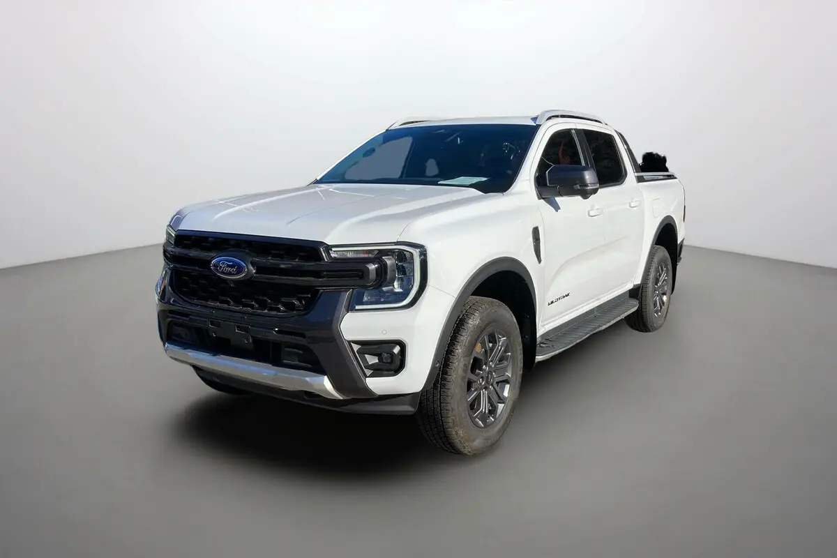 Ford Ranger Wildtrak blanc glacier en 3/4 avant droit avec barres de toit et marchepieds visibles.