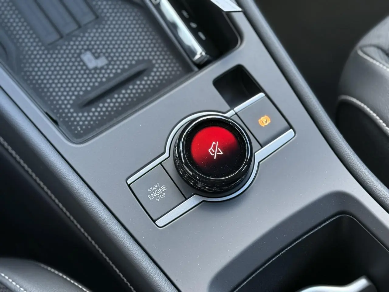 Gros plan sur la molette de commande centrale rouge et les boutons environnants dans l'habitacle noir du Volkswagen T-Roc.