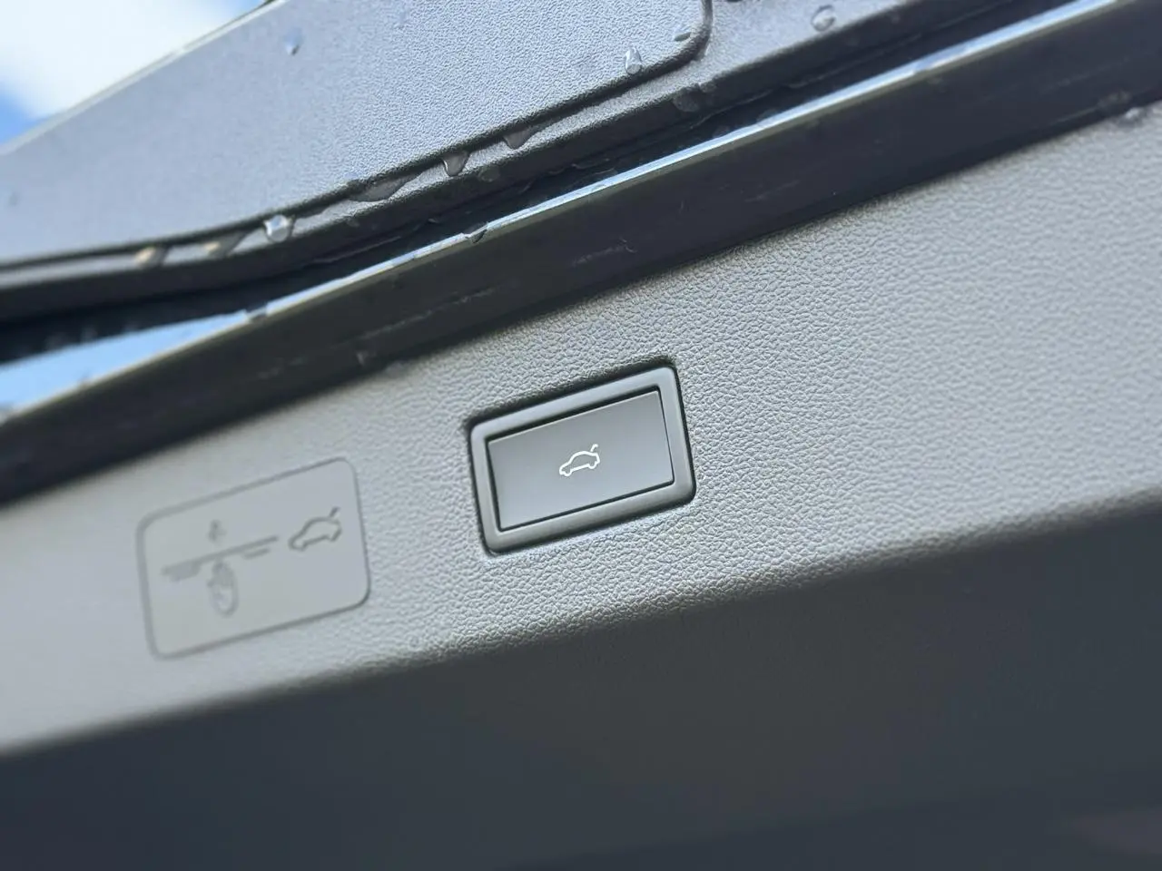 Gros plan sur le bouton d'ouverture électrique du hayon du Volkswagen T-Roc 2026, intérieur noir.