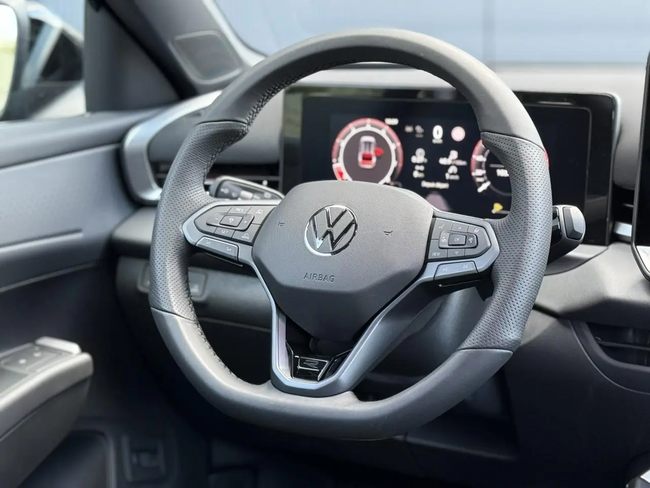 Vue rapprochée du volant sport multifonction noir du Volkswagen T-Roc 2026 avec tableau de bord numérique en arrière-plan.