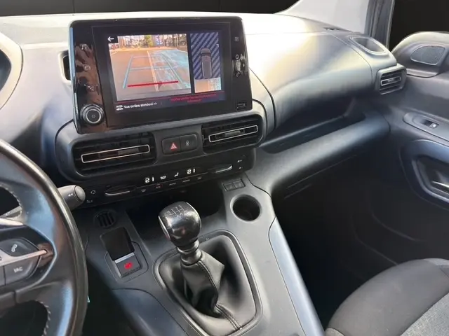 Vue intérieure côté passager du tableau de bord et console centrale du Peugeot Rifter gris foncé avec écran tactile et levier de vitesse manuel.