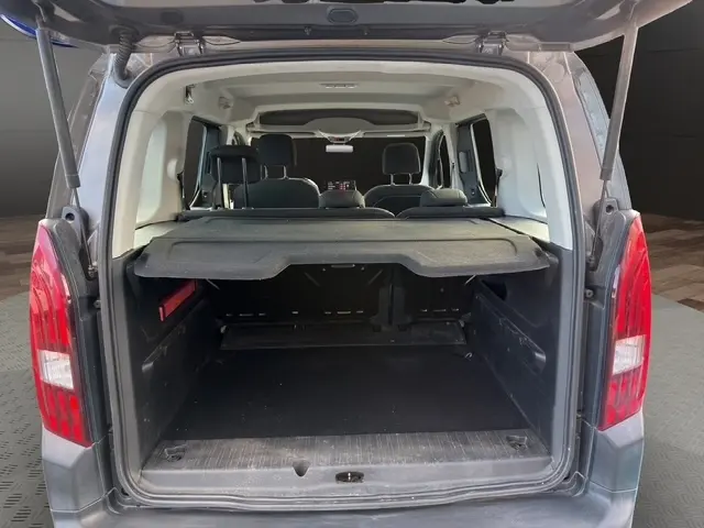 Vue arrière ouverte du Peugeot Rifter gris foncé 2020, montrant le coffre spacieux avec tablette de séparation et banquette arrière.