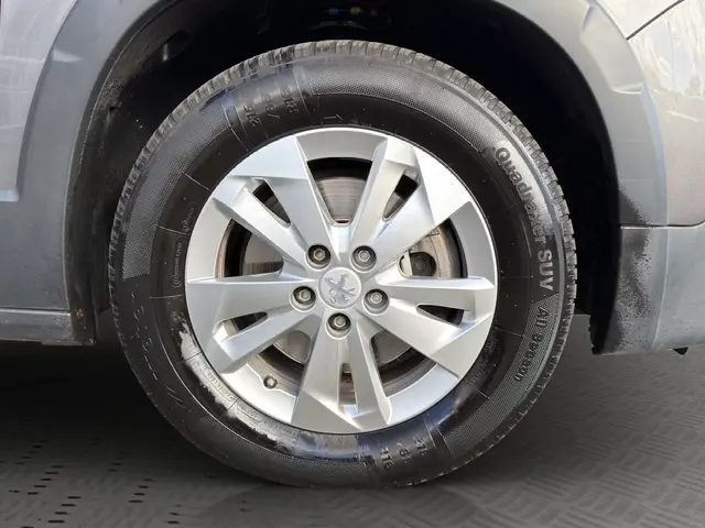 Gros plan sur la roue avant droite d’un Peugeot Rifter gris foncé, mettant en valeur la jante en alliage et le logo Peugeot central.