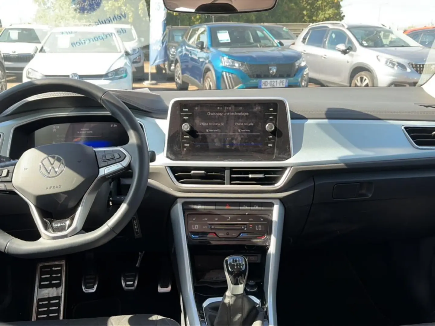 Vue intérieure avant du Volkswagen T-Roc blanc, avec tableau de bord moderne et volant multifonction noir.