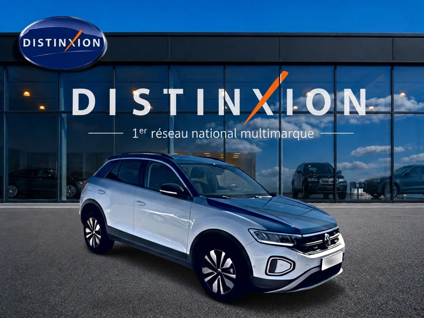 Volkswagen T-Roc blanc vue 3/4 avant droit devant un bâtiment avec logo Distinxion.