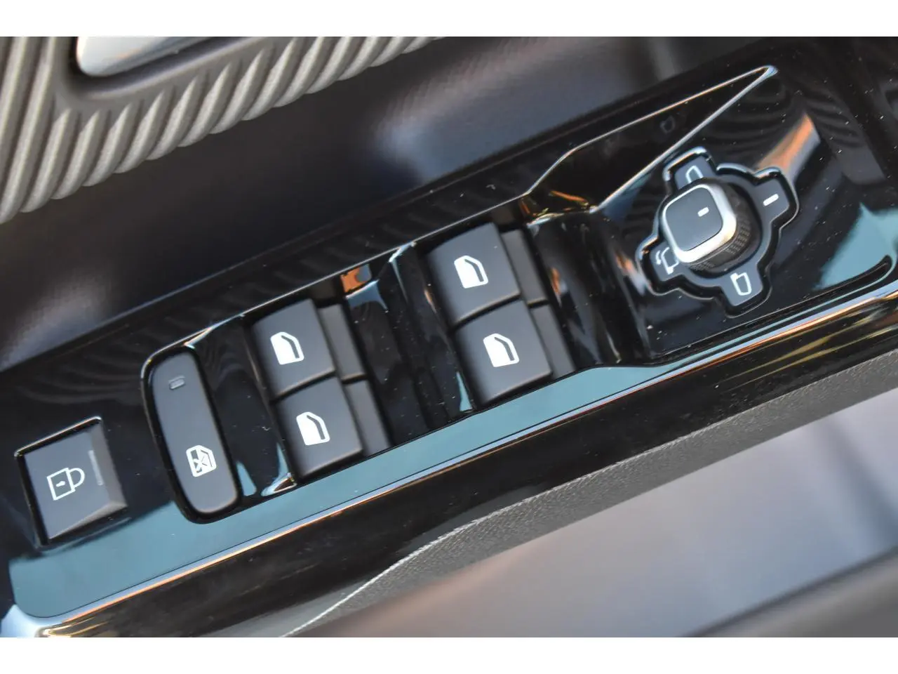 Gros plan sur les commandes de lève-vitres et réglages des rétroviseurs côté conducteur du Citroën C5 Aircross hybride gris.