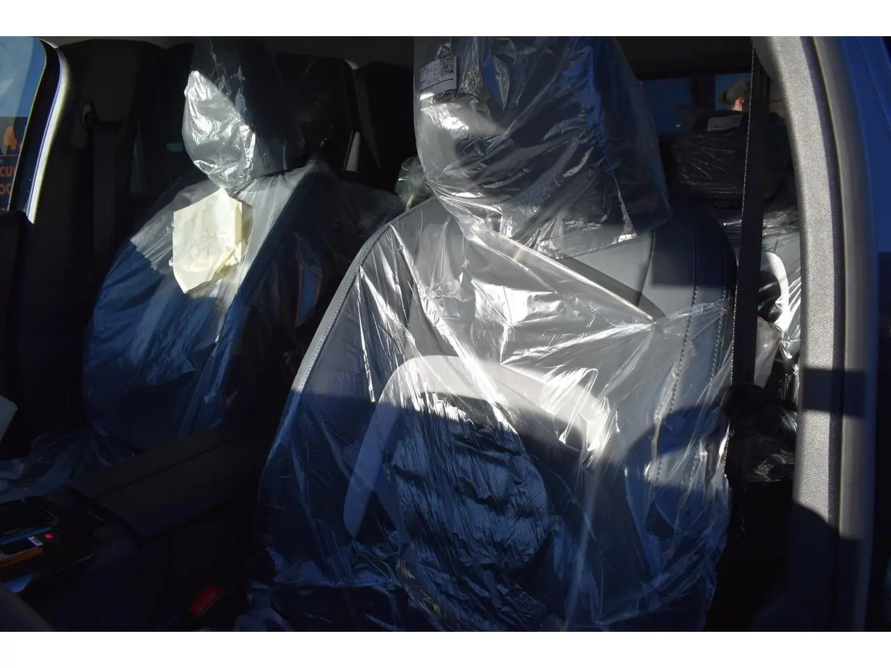 Gros plan sur les sièges avant protégés par des housses plastiques dans l'habitacle du Citroën C5 Aircross gris.