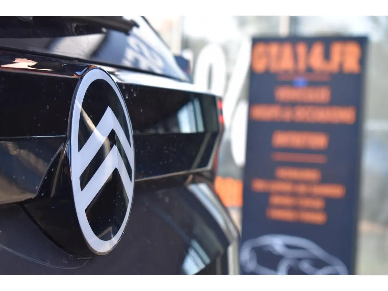 Gros plan sur l'arrière noir brillant d'un Citroën C5 Aircross avec le logo chromé en relief.