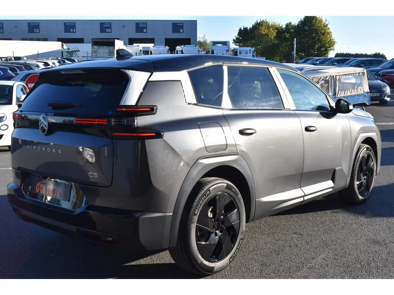 Vue 3/4 arrière droite du Citroën C5 Aircross gris métallisé avec toit bi-ton noir et jantes noires.