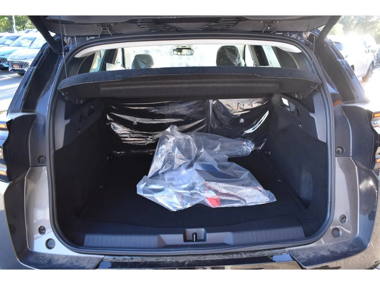 Vue arrière du coffre ouvert d'un Citroën C5 Aircross gris, montrant un espace de chargement vide avec un objet emballé en plastique.