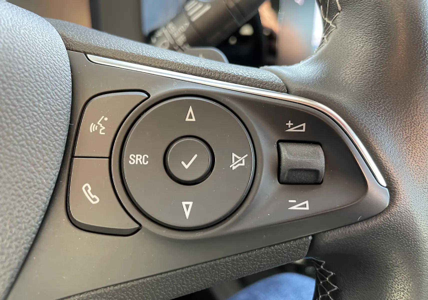 Gros plan sur les commandes audio et téléphone au volant noir de l'Opel Mokka 2023 finition Elegance Business.