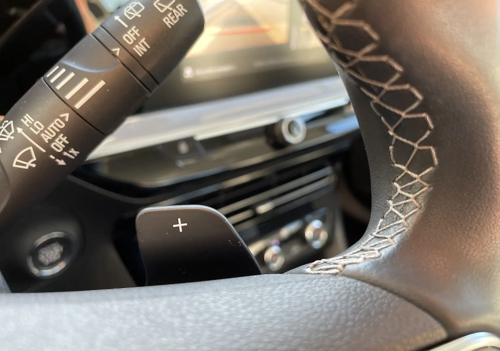 Gros plan sur la palette de changement de vitesse + au volant avec surpiqûres, tableau de bord et commandes de l’Opel Mokka 2023.