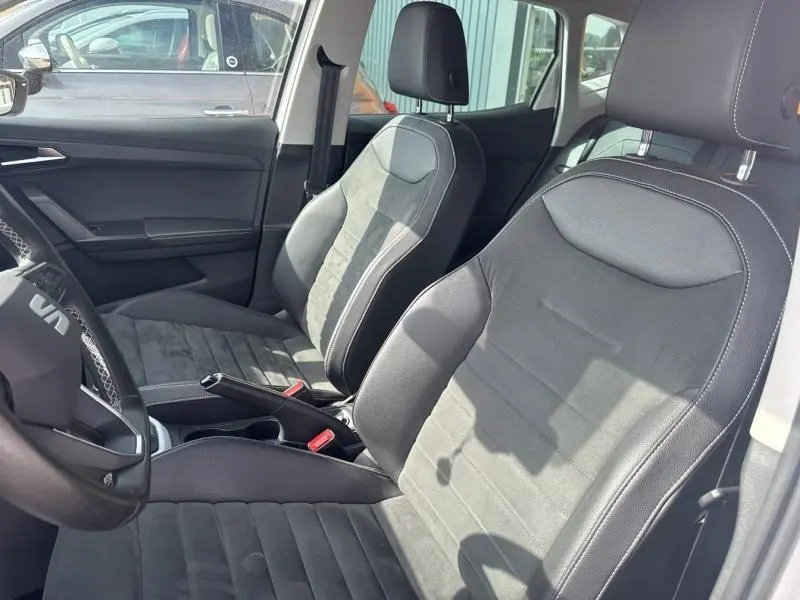 Vue intérieure côté conducteur du SEAT Arona 2022, sièges tissu gris et cuir noir avec surpiqûres blanches.