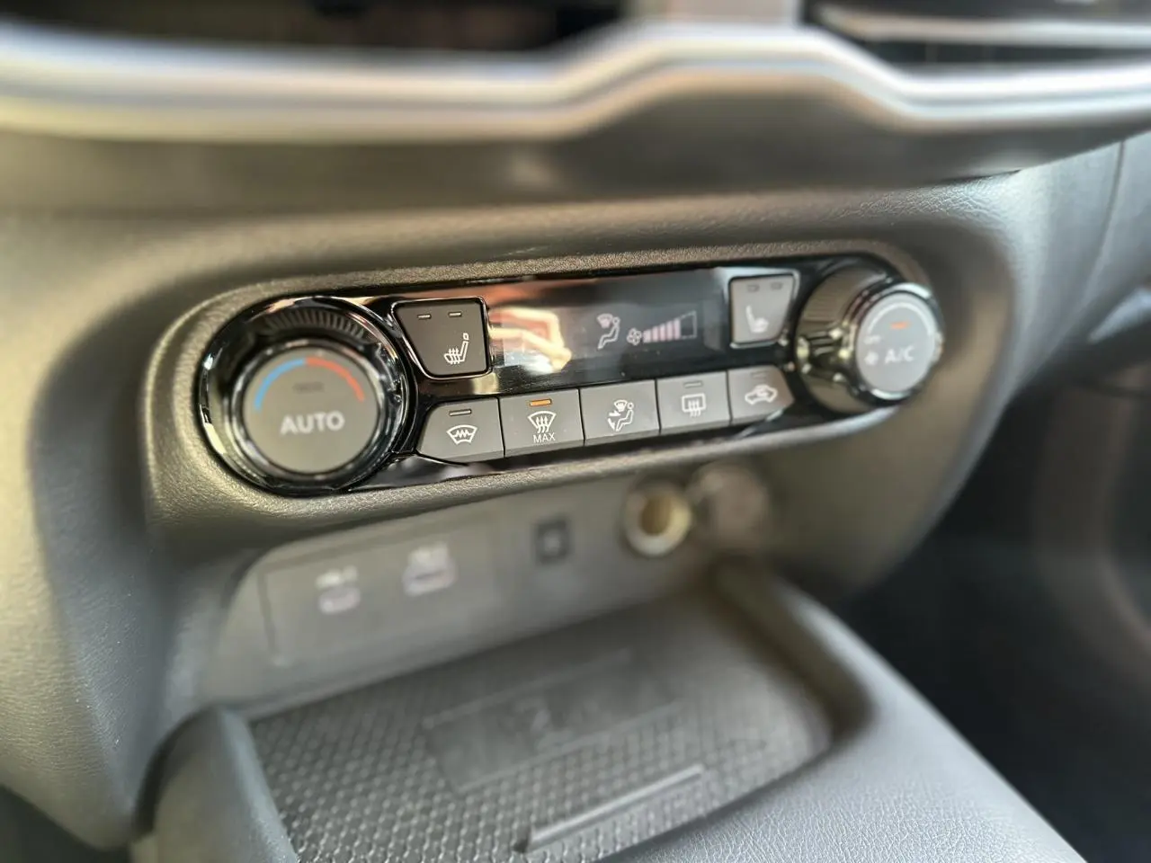 Gros plan sur la console centrale noire du Nissan Juke 2025, mettant en valeur les commandes de climatisation et sièges chauffants.