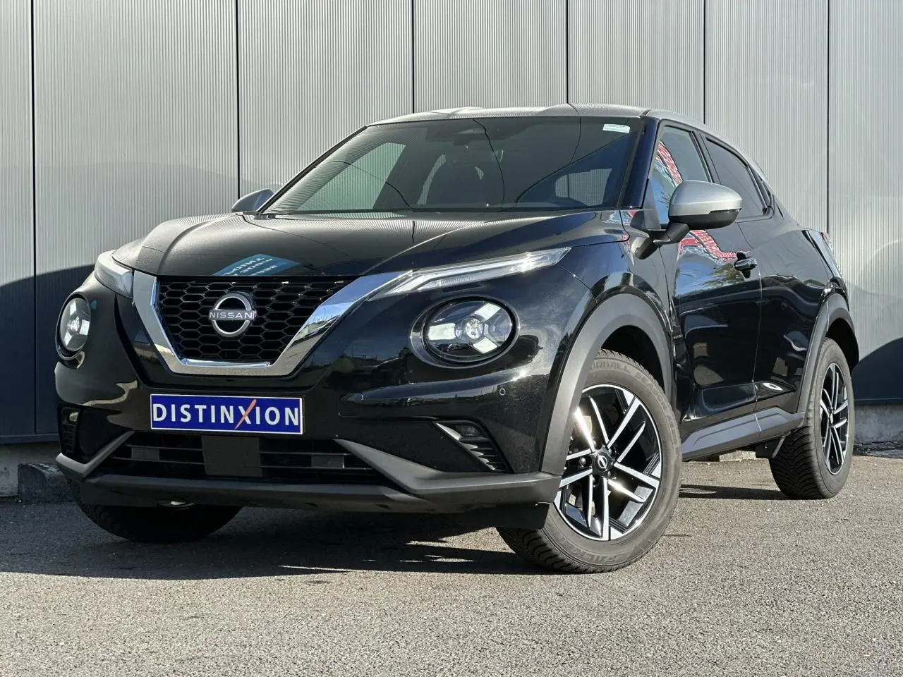 Nissan Juke noir en 3/4 avant droit, avec jantes alliage et calandre chromée brillante.