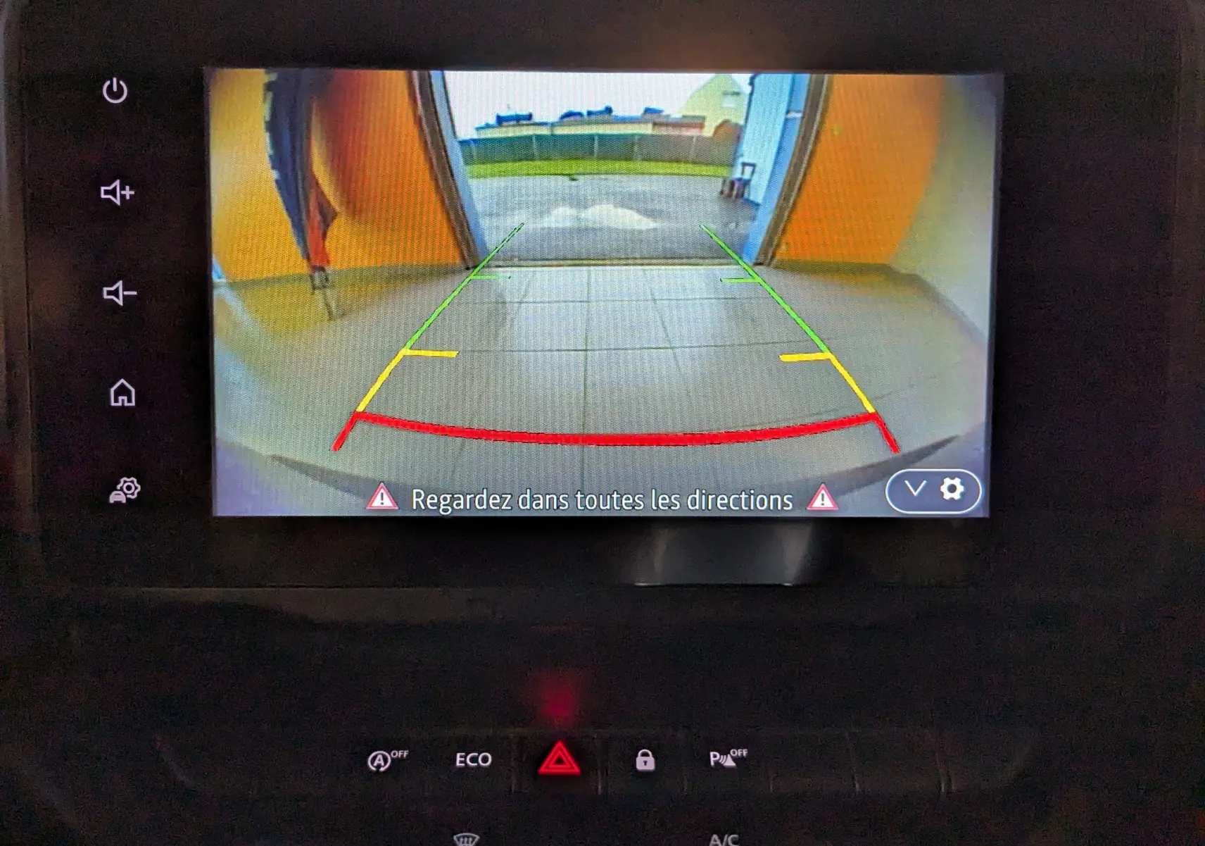 Écran de caméra de recul du Dacia Duster gris 2023 montrant une porte de garage ouverte avec guidage coloré.