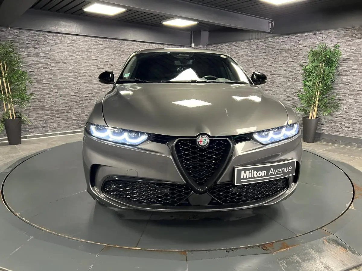 Vue frontale d'une Alfa Romeo Tonale gris foncé avec phares LED allumés et calandre en V distinctive.