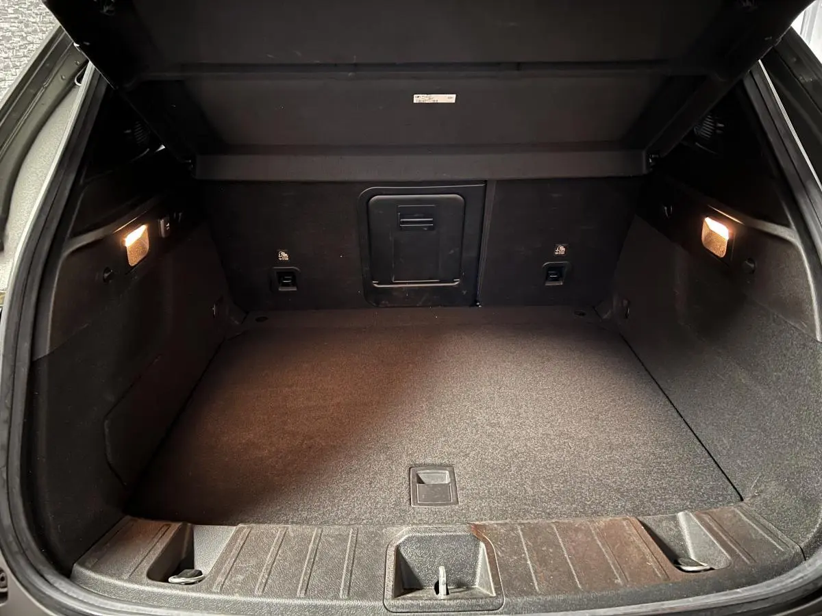 Coffre ouvert vu de l'arrière d'une Alfa Romeo Tonale gris foncé, intérieur spacieux et éclairage latéral allumé.