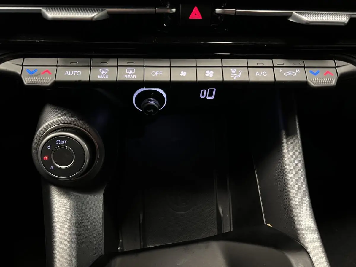 Vue rapprochée de la console centrale noire de l'Alfa Romeo Tonale 2022 avec commandes climatisation et molette de sélection.
