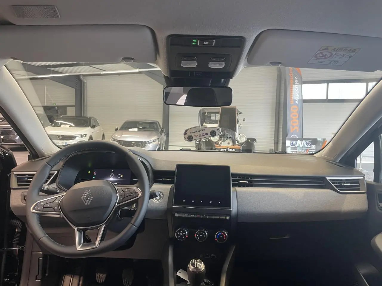 Vue intérieure avant de la Renault Clio 2025 avec volant multifonction, écran tactile 7 pouces et levier de vitesse manuel.