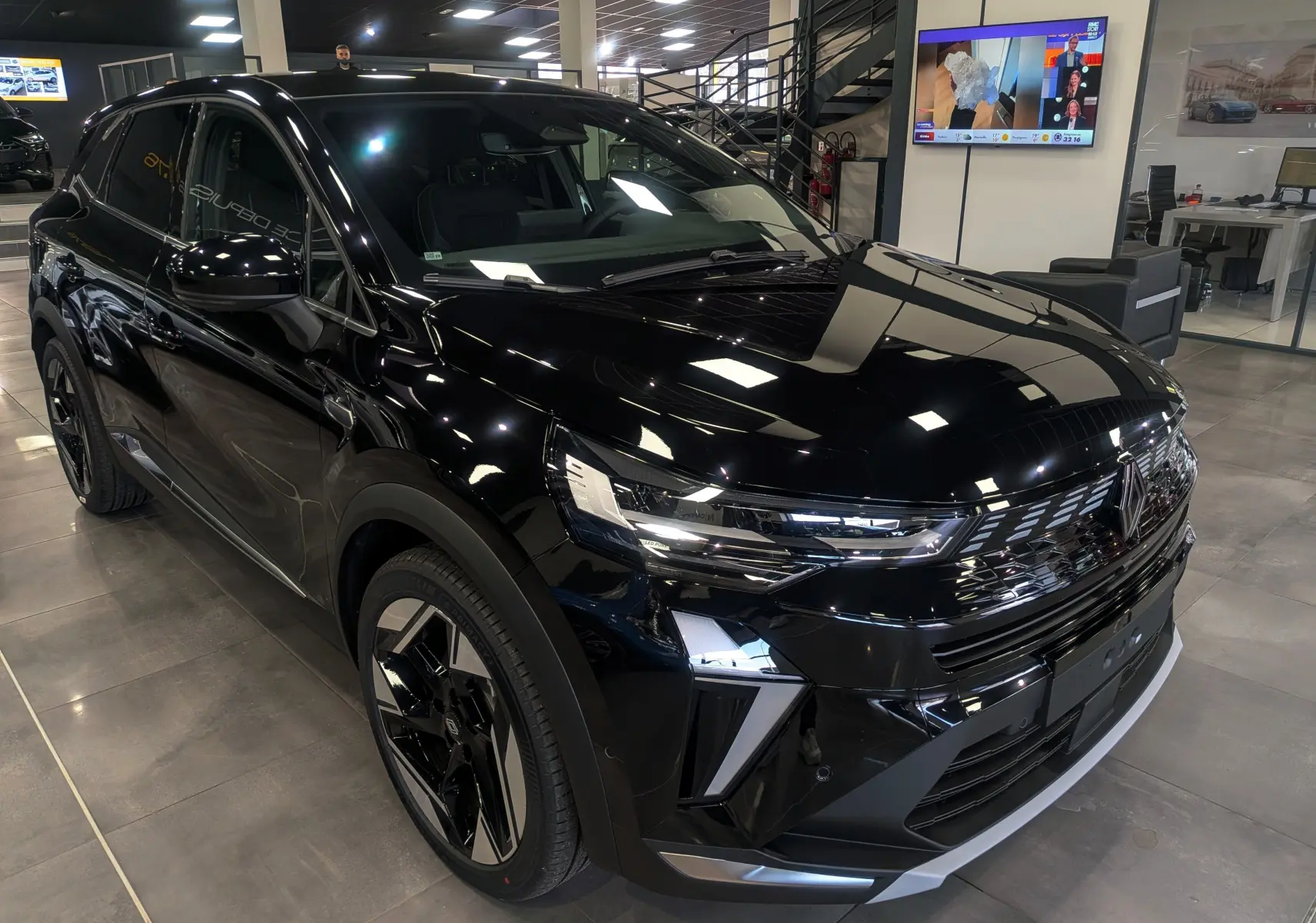 Vue 3/4 avant d’un Renault SYMBIOZ E-Tech full hybrid noir étoilé, avec calandre et phares LED distinctifs en showroom.