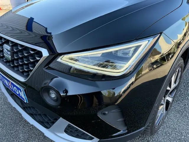 Gros plan sur l'avant droit du SEAT Arona noir avec toit gris, mettant en valeur le phare LED et la calandre distinctive.