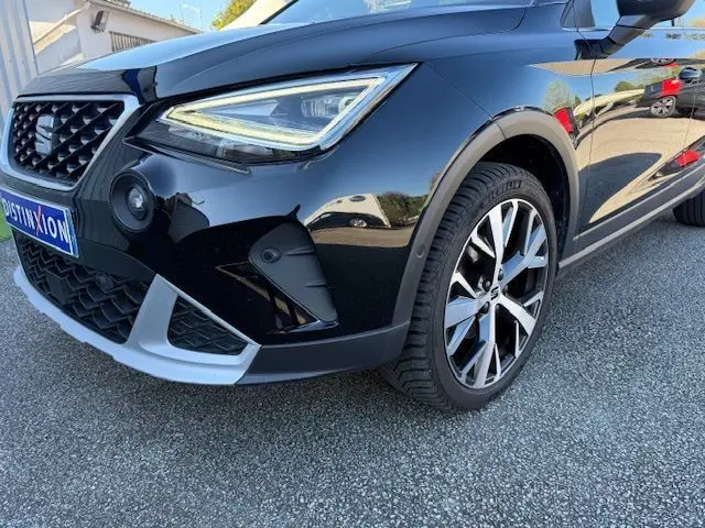 Gros plan sur l’avant droit noir du SEAT Arona 2022 avec jante alliage 18'' et projecteur LED distinctif.