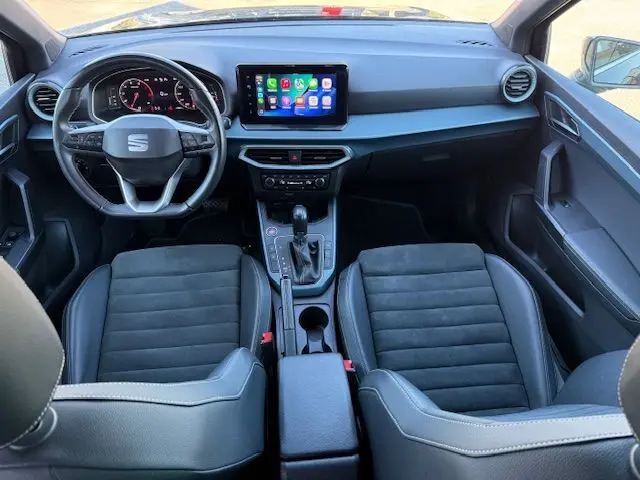 Vue intérieure avant du SEAT Arona 2022 noir, avec tableau de bord numérique et écran tactile central.