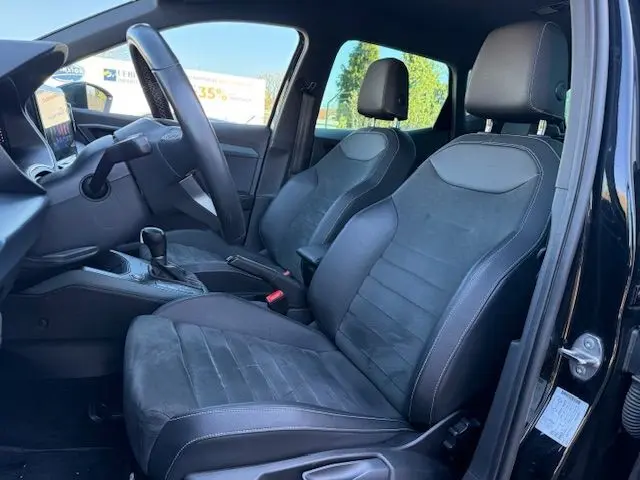 Vue intérieure côté conducteur du SEAT Arona noir 2022, mettant en valeur les sièges en suédine noire et la console centrale.