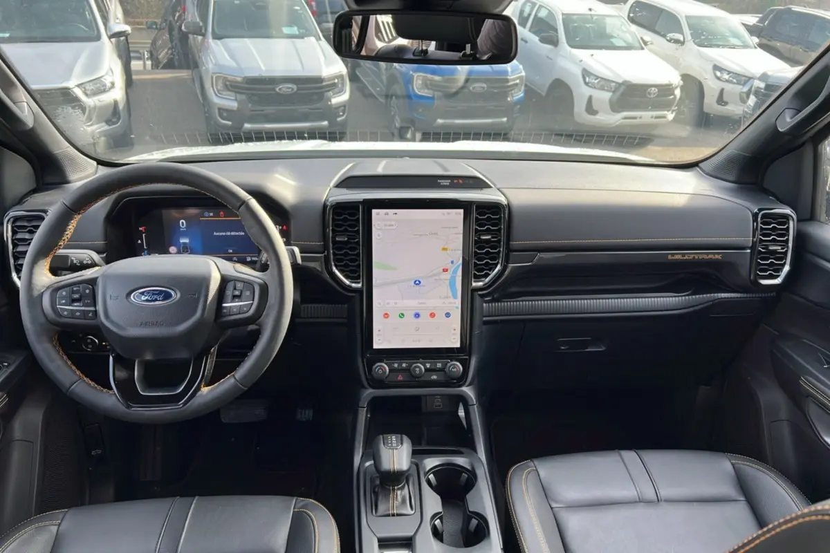 Vue intérieure frontale du tableau de bord du Ford Ranger Wildtrak 2026 avec écran tactile vertical et volant cuir noir.