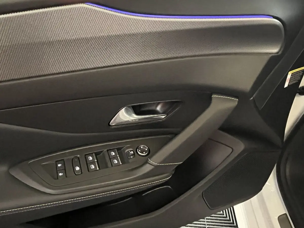 Détail de la porte côté conducteur de la Peugeot 308 GT PHEV 180 blanc nacré, avec commandes de vitres et poignée chromée.