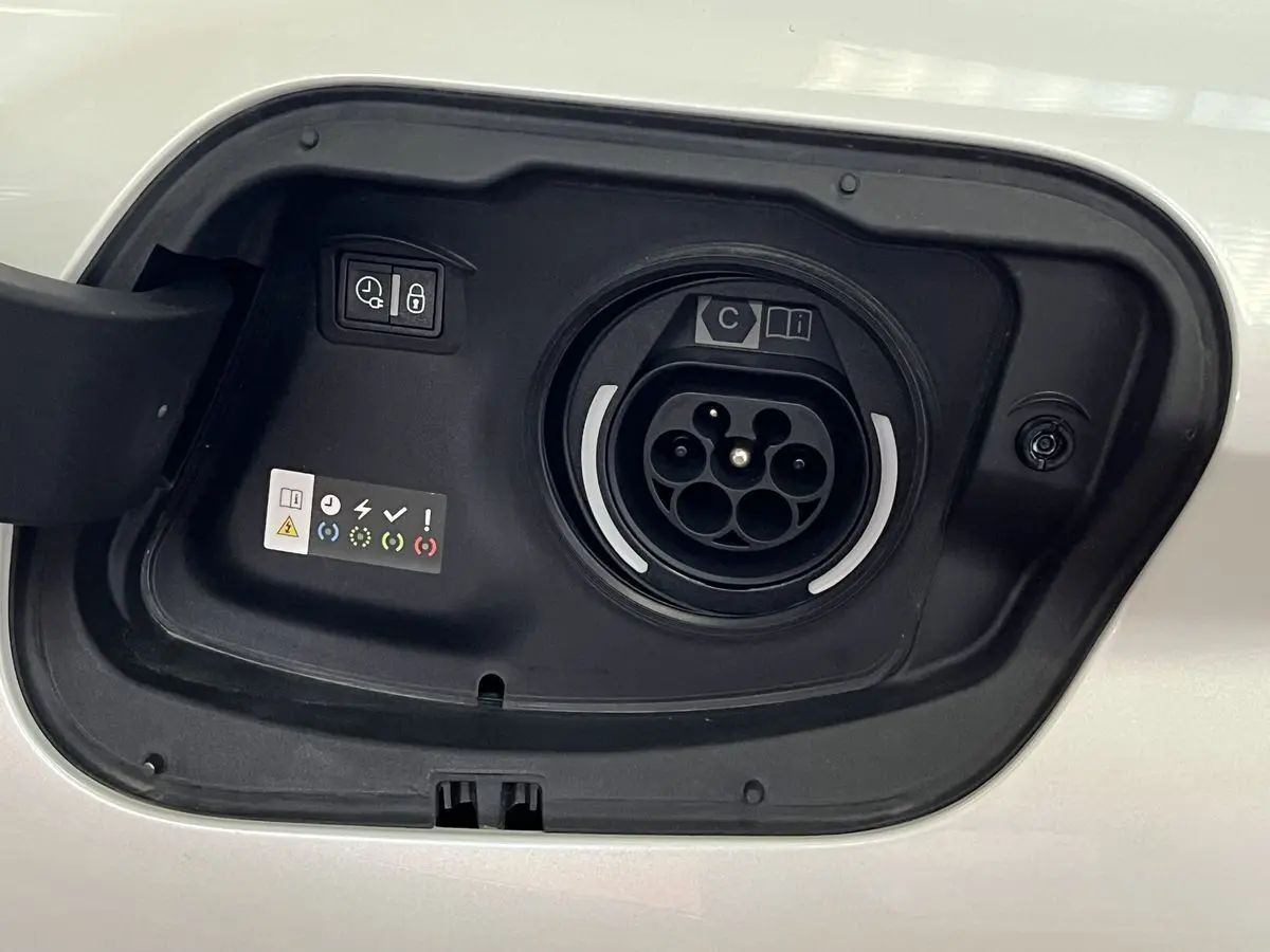 Détail de la trappe de recharge hybride blanche nacrée d'une Peugeot 308 GT PHEV 180 vue de près.