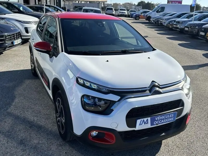 Citroën C3 2021 blanc avec toit rouge, vue 3/4 avant droit, détails rouges sur pare-chocs et rétroviseur.