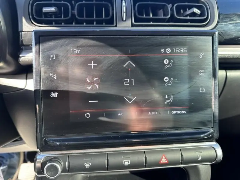 Écran tactile central du tableau de bord du Citroën C3 blanc toit rouge, affichant la climatisation à 21°C.