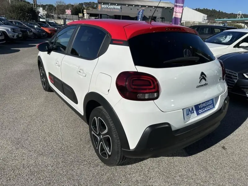Vue 3/4 arrière droite d'une Citroën C3 2021 blanche avec toit rouge et détails noirs contrastants.