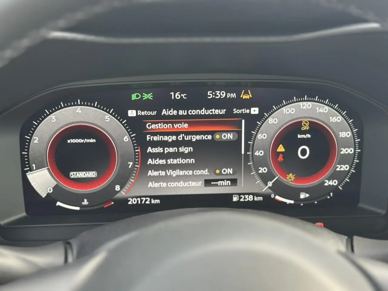 Tableau de bord digital du Nissan Juke 2025 affichant l'aide au conducteur et compte-tours en vue frontale.