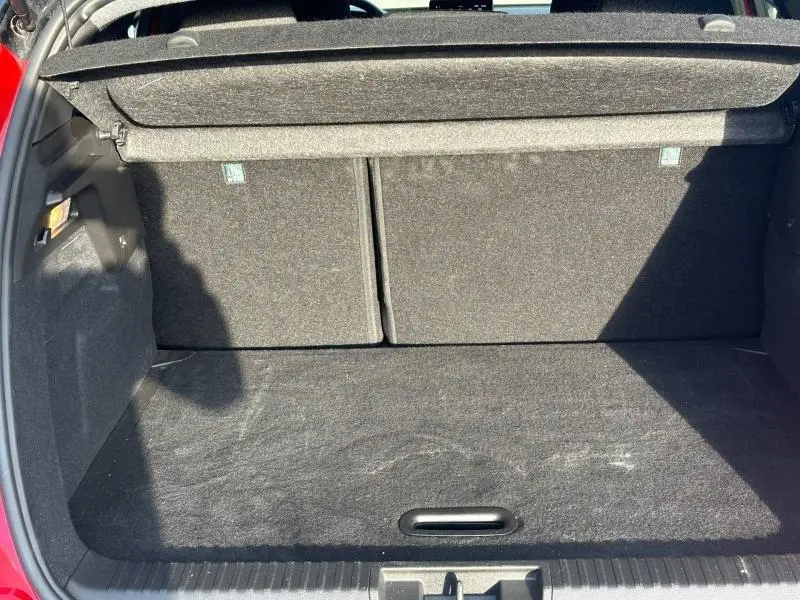 Coffre ouvert vu de l'arrière d'un Renault Captur 2025 Rouge Flamme/Noir Étoilé, montrant l'espace de chargement vide.