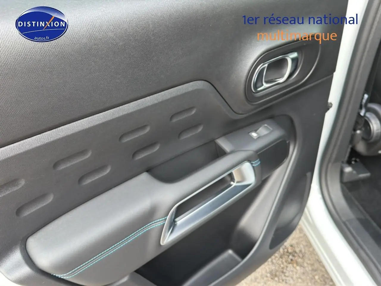 Détail de la porte avant droite noire avec surpiqûres bleues du Citroën C5 Aircross blanc 2025.