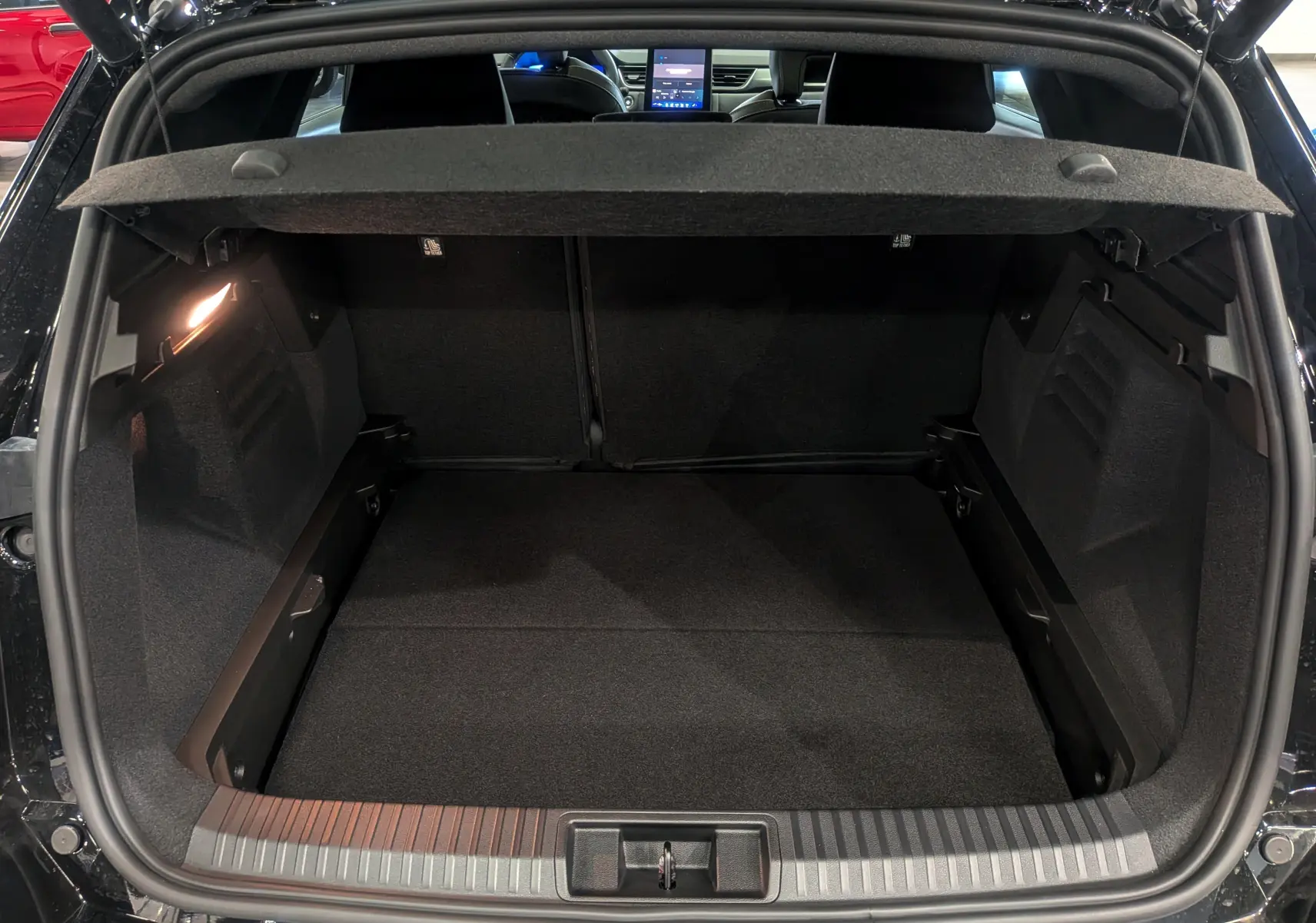 Coffre ouvert vu de l'arrière d'une Renault SYMBIOZ noir étoilé, avec intérieur spacieux et tablette de séparation.