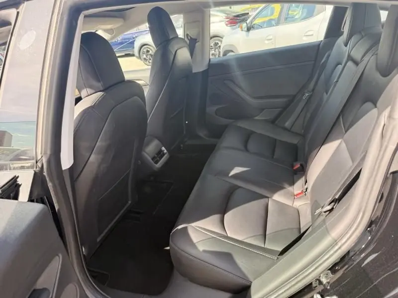 Vue intérieure arrière droite du Tesla Model 3 noir 2022, montrant les sièges en cuir et l'espace passagers.