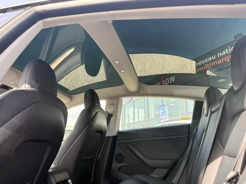 Intérieur arrière de la Tesla Model 3 noir 2022, vue côté droit avec toit panoramique en verre et sièges en cuir noir.