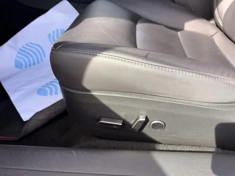 Gros plan sur le siège avant gauche en cuir noir du Tesla Model 3 Standard RWD Plus 2022, avec commandes électriques visibles.