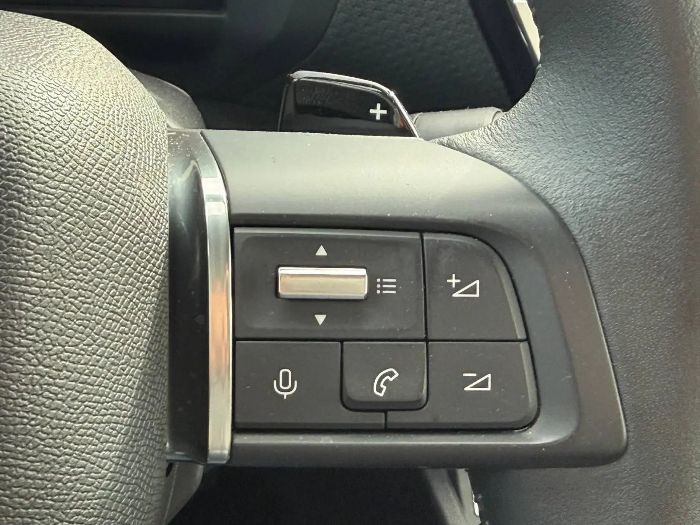 Gros plan sur les commandes vocales et téléphoniques au volant cuir noir de la Citroën C4 hybride 2025.
